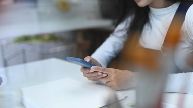 young woman sitting at desk and look at smartphone screen